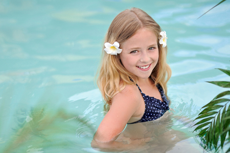 portrait of little girl in tropical style in a swimming poolの写真素材