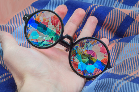 Designer glasses with lenses of a kaleidoscope lie on the handの写真素材