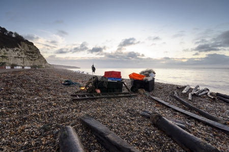 Fishing boxes and nets on the beachat sunrise at Beer in Devonの写真素材