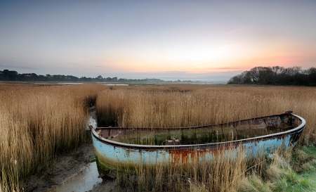 Rusty old abandoned shipwrecked boat in reeds in the backwaters of Poole Harbour in Dorset の写真素材