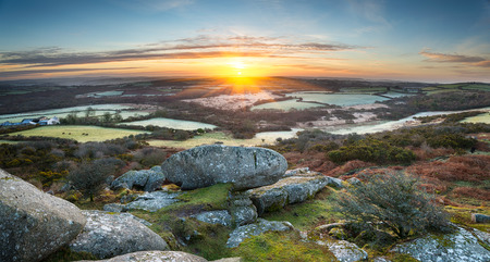 A frosty early spring sunrise looking out over a patchwork of fields and rolling hills at Helman Tor a rocky outcrop of rugged moors near Bodmin in Cornwallの写真素材