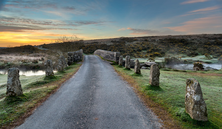 Country lane in Dartmoor crossing an ancient granite bridge over the East Dart River at Belleverの写真素材