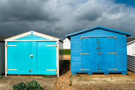 Blue beach huts under a dramatic sky at St Leonards on Sea in Hastings, East Sussexの写真素材