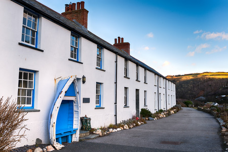 A row of white terraced cottages with an old boat seat at Boscastle in Cornwallの写真素材