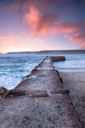 Dramatic sunset sky over the pier at Sennen Cove in the far west of Cornwallの写真素材
