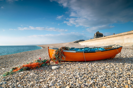 Orange fishing boat on Chesil Beach at Portland near Weymouth on the Jurassic Coast of Dorsetの写真素材
