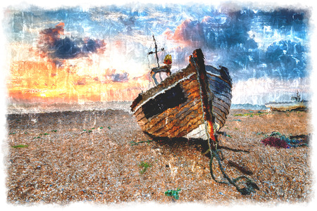 A beautiful sunrise over a wooden fihing boat on s shingle beachの写真素材