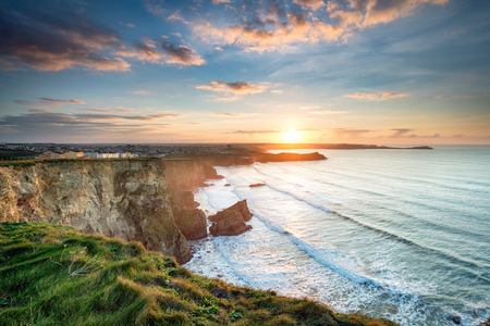 Stunning dramatic sunset from cliffs over Whipsiderry Beach at Porth in Newquay, Cornwall