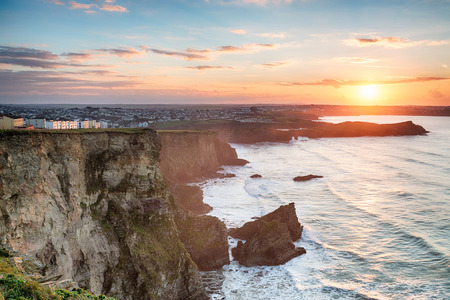 A stunning hazy sunset over cliffs at Porth on the outskirts of Newquay on the Cornwall coastの写真素材