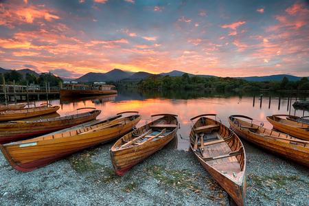 Stunning sunset over wooden rowing boats on Derwentwater at Keswick in the Lake District Nationla Park in Cumbriaの写真素材