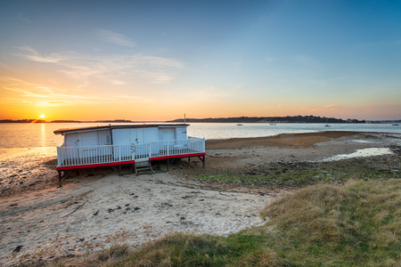 Sunset over an old houseboat on the beach at Bramble Bush bay on Studland on the Purbeck coast of Dorsetの写真素材