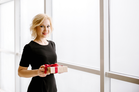 The beautiful girl holds a gift or a surprise in handの写真素材