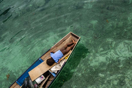 Mabul Island, Sabah, Malaysia- August 08,2018 : A kid on the small boat, floating on the blue beach. They are know as 'bajau laut' attraction for touristのeditorial素材