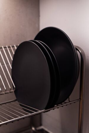 Black color plate arranged on silver color dish drainer. Image contains excessive noise