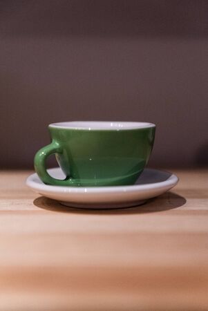 Green small cup on the table. Image contains excessive noiseの写真素材