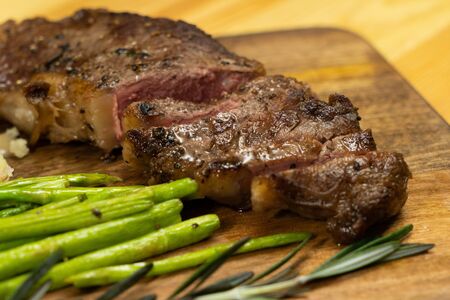 Ready to eat beef steak with asparagus on wooden chopping boardの写真素材
