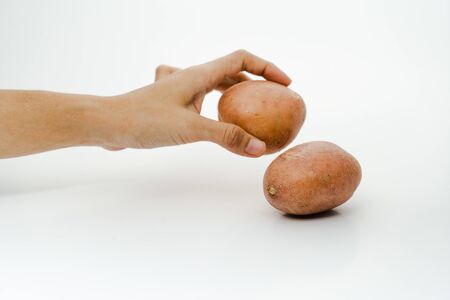A young woman put a potato on the table. Two fresh potatoes isolated on white background with selective focusの写真素材