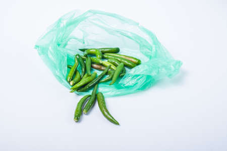 A green chili without a stalk in a green plastic bag. Isolated on white backgroundの写真素材