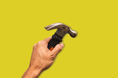 Top angle of a young man holding hammer on yellow backgroundの写真素材
