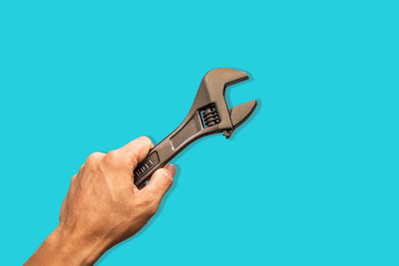 Top angle of a young man holding adjustable wrench on blue backgroundの写真素材