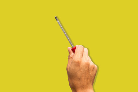 Top angle of a young man holding screwdriver philip on yellow backgroundの写真素材