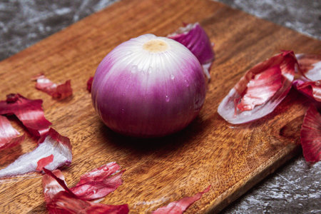 A peeled onion, on wooden cutting board and black backgroundの写真素材