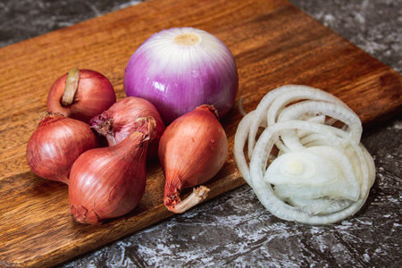A group of onion on wooden cutting board and black backgroundの写真素材