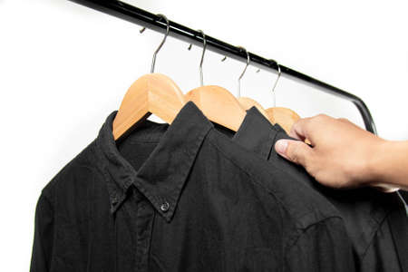 A businessman chooses shirt on the black hanger before go to work or before a night out. Choose a cotton black shirtの写真素材