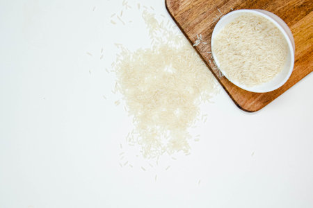 Bowl of long grain white rice, on black walnut chopping board isolated on white background. Copy spaceの写真素材