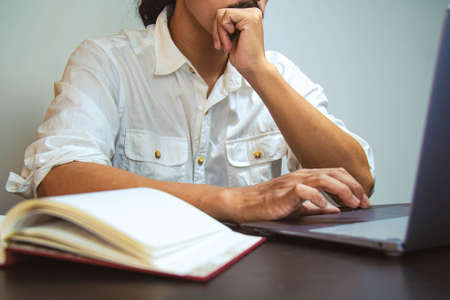 A young man with mustache wearing a white shirt. Thinking and looking to his laptop. Selective focus shot. Vintage filter applied. Copy space. Business concept.の写真素材