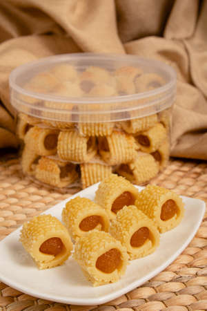 Delicious homemade pineapple roll tart for eid fitr on a with plate. Containers as a backgroundの写真素材