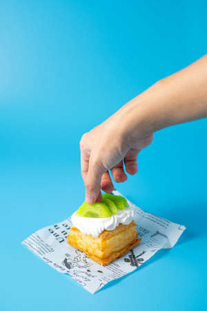 puff pastry pie with fresh fruits. Hand holding slice of strawberryの写真素材