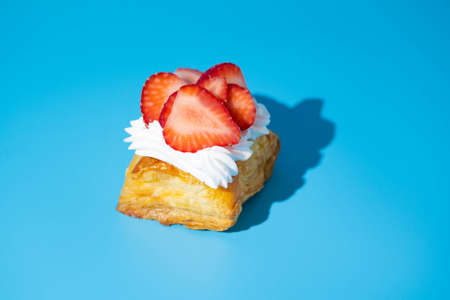 puff pastry pie with fresh fruits. Hand holding slice of strawberryの写真素材