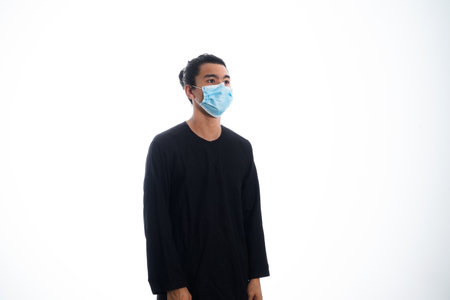 health, pandemic and safety concept - asian young man wearing face protective medical mask for protection from virus disease over white backgroundの写真素材
