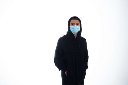health, pandemic and safety concept - asian young man wearing face protective medical mask for protection from virus disease over white backgroundの写真素材