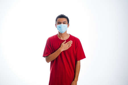 health, pandemic and safety concept - asian young man wearing face protective medical mask for protection from virus disease over white backgroundの写真素材