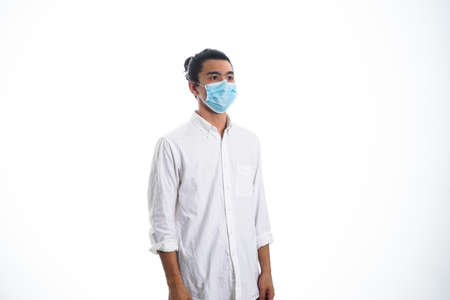 health, pandemic and safety concept - asian young man wearing face protective medical mask for protection from virus disease over white backgroundの写真素材