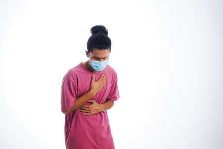 the concept of health care and medicine. A young man standing in a face mask with hand gesture "i'm sick", supporting social distanceの写真素材