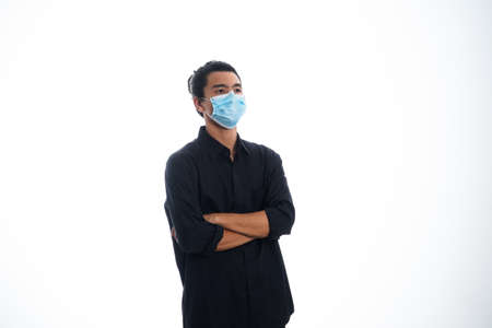 health, pandemic and safety concept - asian young man wearing face protective medical mask for protection from virus disease over white backgroundの写真素材