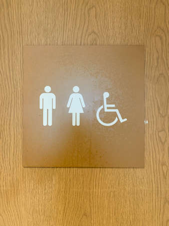 Man,woman, and disable restroom sign on wooden doorの写真素材