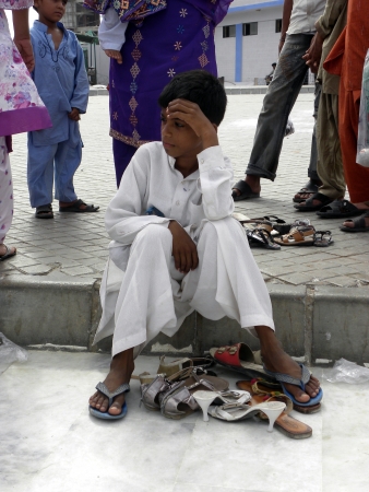 PAKISTAN/KARACHI_BOY SITTING ON GROUND DUE TO TAKING CARE OF HIS FAMILY SHOES TODAY ON FRIDAY 18 MAY 2012 IN KARACHI                               のeditorial素材