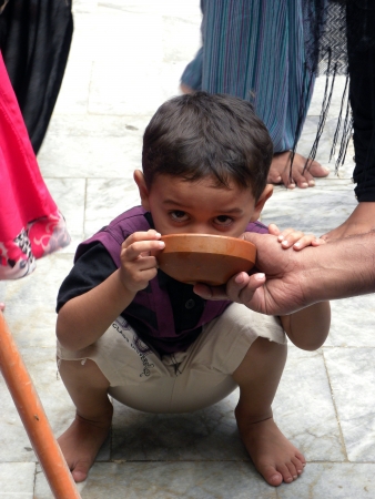 PAKISTAN/KARACHI_CHILD DRINKING WATER SITTING DOWN ON GROUNG TODAY ON SATURDAY 19 MAY 2012                                                            のeditorial素材
