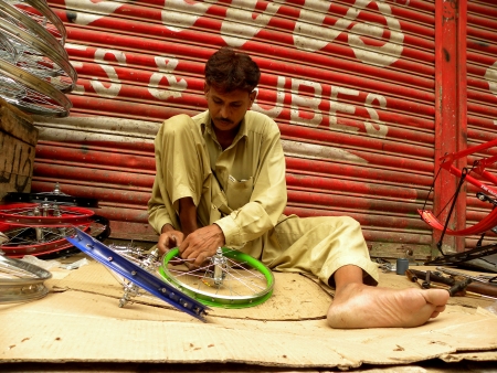PAKISTAN/KARACHI_LOCAL MAN INSTALLING NEW CYCLE PARTS FOR BRAND NEW CYCLE TO SALE IN MARKET TODAY ON FRIDAY 10 AUGUST 2012 IN KARACHI LIGHT HOUSE                                      のeditorial素材