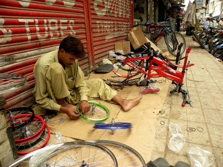 PAKISTAN/KARACHI_LOCAL MAN INSTALLING NEW CYCLE PARTS FOR BRAND NEW CYCLE TO SALE IN MARKET TODAY ON FRIDAY 10 AUGUST 2012 IN KARACHI LIGHT HOUSE              のeditorial素材