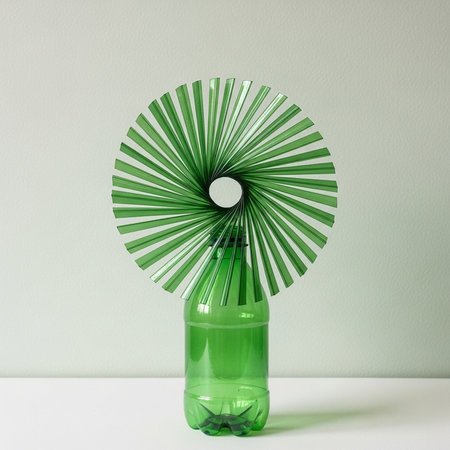 Green glass bottle on a white table with a decorative fan in the form of a fanの素材