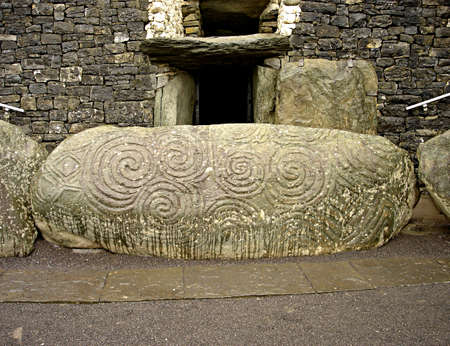 An ancient, massive boulder inscribed with early celtic spiral drawings in front of the main entrance at Newgrange in Irelandの写真素材