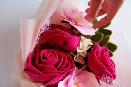 girl hand touching beautiful pink flower bouquet with roses, daisy, and greeneryの写真素材