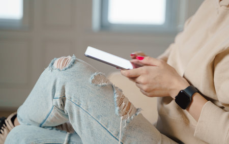 Close up of caucasian woman sitting on sofa in living room and touching tablet.の写真素材