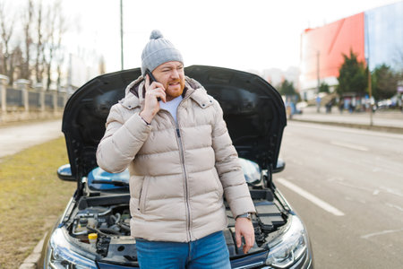 A lone man, looking unhappy and stressed, stands by his damaged vehicle on the side of the road,