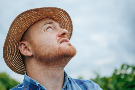 Dreamy male farmer looking away against cloudy skyの写真素材